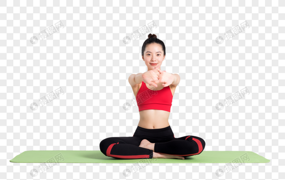 坐在瑜伽垫上做伸展运动的女性图片