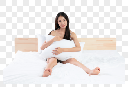 年轻女性抱着枕头在床上图片