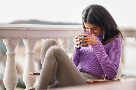 微笑的女人坐阳台上的扶手椅上喝着杯咖啡波斯女人阳台上喝了杯咖啡图片