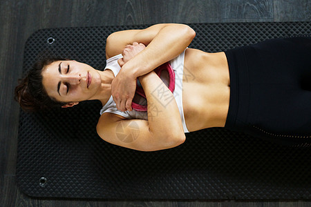 运动的年轻女性,穿着运动服,瑜伽垫上做仰卧起坐,健身房里举重健身妇女做腹肌锻炼年轻的女运动员瑜伽垫上做仰卧起坐图片