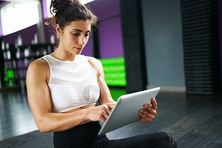 运动女性健身房用她的智能手机咨询她的训练女人智能手机上咨询她的培训图片