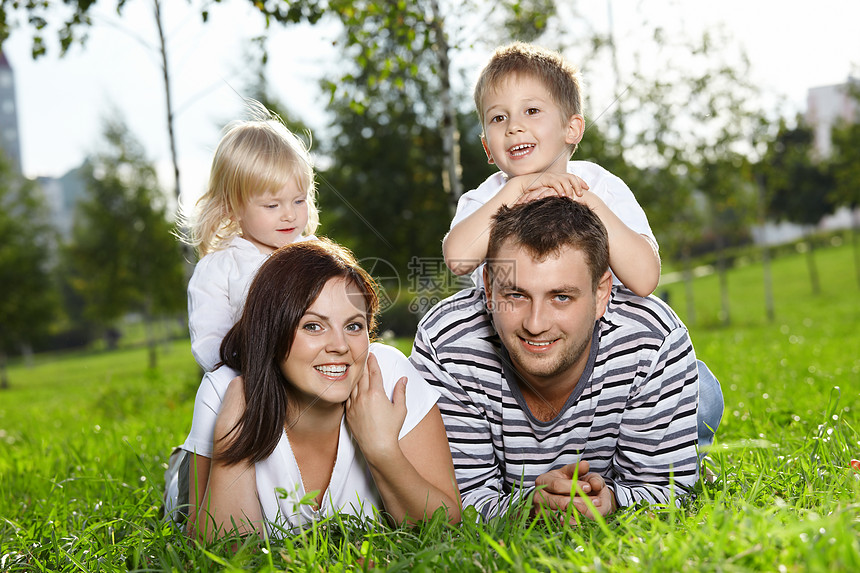 来自四个人的幸福家庭躺夏天的草坪上图片
