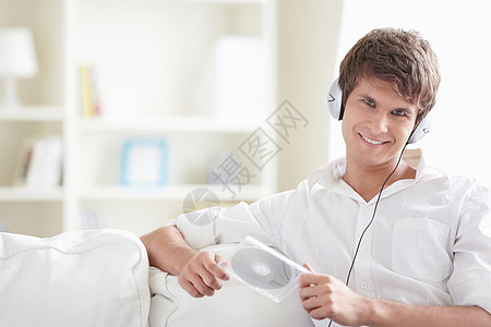 有吸引力的人,手里着个磁盘,沙发上的耳机听音乐图片