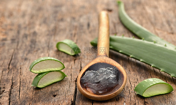 芦荟片木制桌子勺子与芦荟凝胶图片