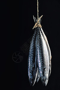 烟熏鲭鱼黑色背景上隔离的绳子上背景图片
