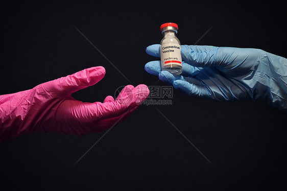 女人用手套给另只手注射冠状病疫苗图片