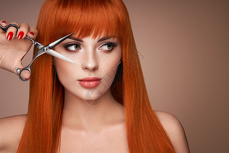 漂亮的年轻女人,化妆明亮,长发光滑,着金属剪刀有红色头发的模特发廊,理发护理美容美发产品完美的化妆背景图片