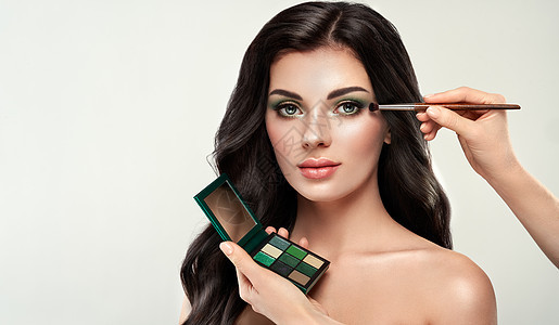 化妆师应用眼影漂亮的女人脸完美的妆容化妆细节美丽的女孩有完美的皮肤指甲指甲眼影调色板图片