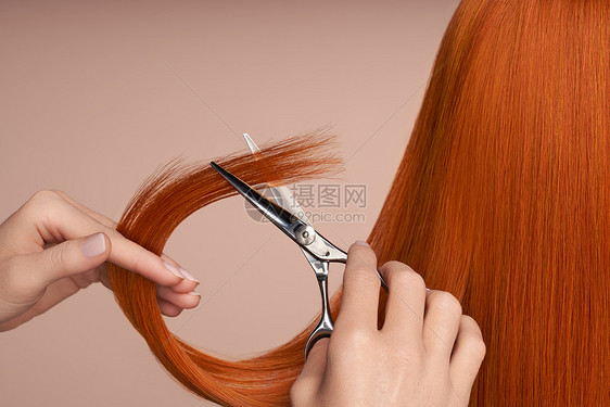 理发师用剪刀剪红色的长发发廊,发型师护理美容美发产品染了头发图片