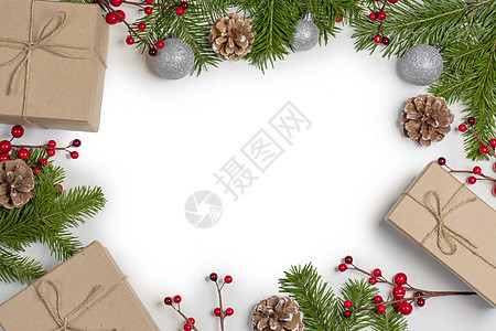 圣诞树树枝上有雪,松果,红色浆果礼品盒,白色背景,有圣诞礼品盒装饰图片