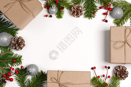 圣诞树树枝上有雪,松果,红色浆果礼品盒,白色背景,有圣诞礼品盒装饰图片