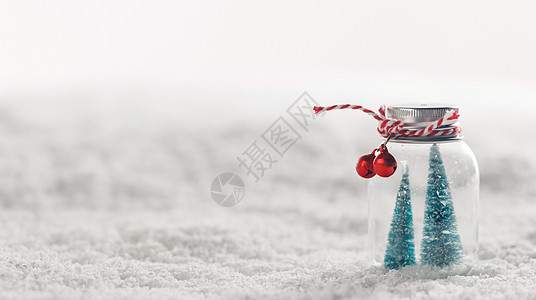 圣诞装饰玻璃罐与条纹丝带,铃铛杉木雪背景雪上的圣诞装饰品图片