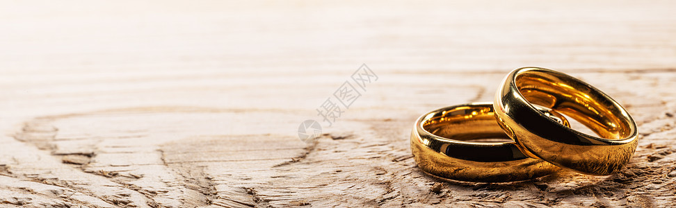 两个金色的结婚戒指木制背景上,有文字的木头上的金色结婚戒指图片