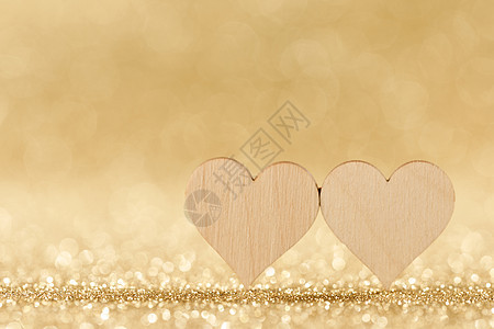 两颗手工制作的小木心明亮的金色灯光下,背景情人节卡片两颗心博克的背景下图片