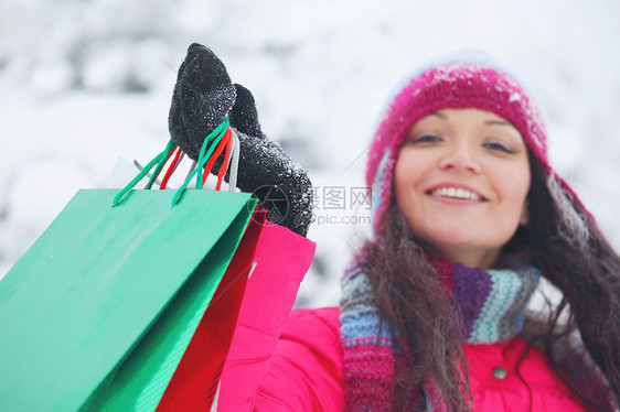 购物快乐的女人白雪覆盖的公园着袋子冬季销售购物妇女着袋子图片