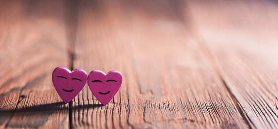 两颗粉红色的微笑心木制背景上,有文字的两颗粉红色的微笑的心图片