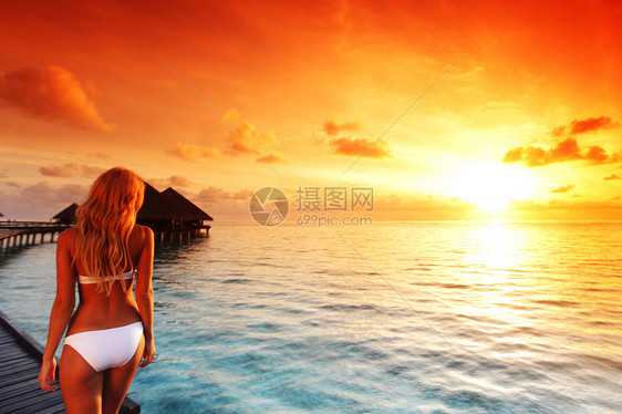 快乐的年轻女人美丽的水别墅马尔代夫岛日落旅游度假旅游胜地马尔代夫岛水上别墅的女人图片