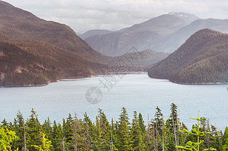 平静的景色加大的山湖旁边,岩石平静的水中反射图片