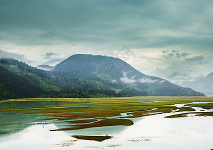 平静的景色加大的山湖旁边,岩石平静的水中反射图片