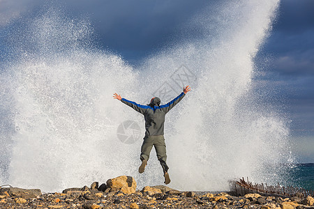 戏剧性的风暴波中跳跃的人图片