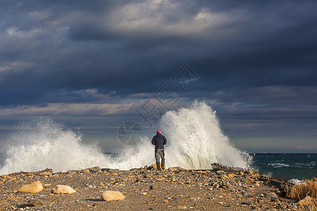 个人站码头上,暴风雨的天气里,大浪拍打着大海图片