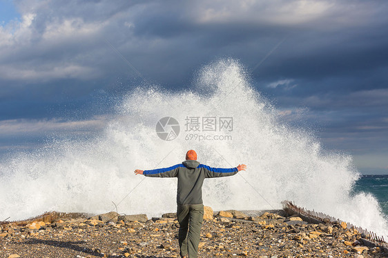 个人站码头上,暴风雨的天气里,大浪拍打着大海图片