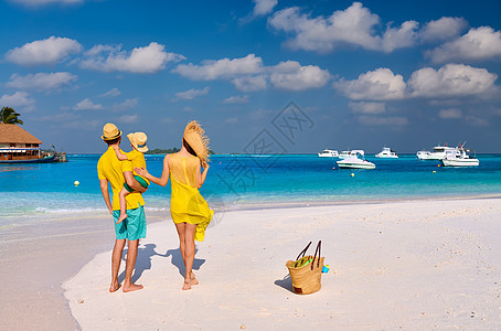海滩上的家人,穿着黄色衣服的年轻夫妇三岁的男孩马尔代夫的暑假图片