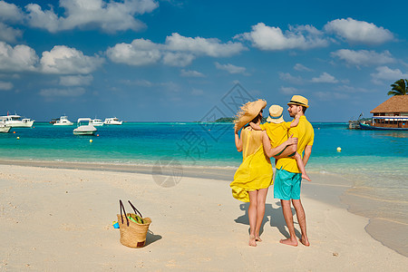 海滩上的家人,穿着黄色衣服的年轻夫妇三岁的男孩马尔代夫的暑假图片