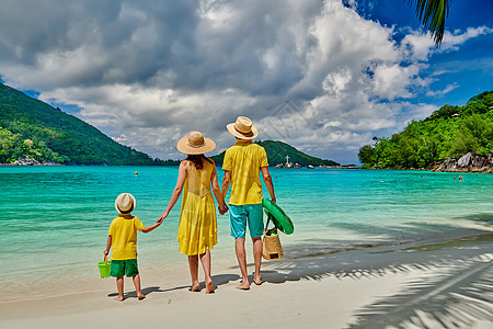 海滩上的家人,穿着黄色衣服的年轻夫妇三岁的男孩塞舌尔的暑假马海港图片