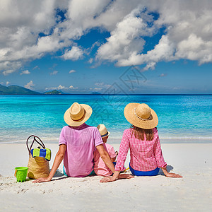 家人美丽的AnseSoleil海滩上,年轻的夫妇三岁的蹒跚学步的男孩马赛尔的暑假背景图片