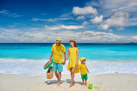 家庭美丽的娇小的Anse海滩,穿着黄色衣服的年轻夫妇三岁的蹒跚学步的男孩马赛尔的暑假背景图片