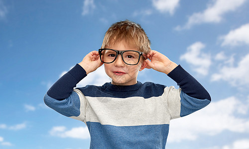 学校,教育视觉微笑的小男孩蓝天云层背景上戴着眼镜的肖像天空上戴眼镜的微笑小男孩的肖像图片