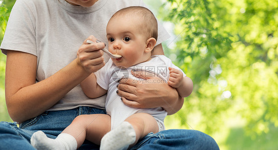 孩子,饮食食物的母亲用勺子喂养小婴儿绿色的自然背景用勺子喂小宝宝来亲近妈妈图片