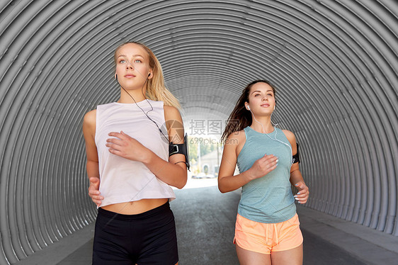 健身运动健康的生活方式年轻女或女朋友戴着带智能手机的,户外跑步带着耳机智能手机的年轻女跑步图片