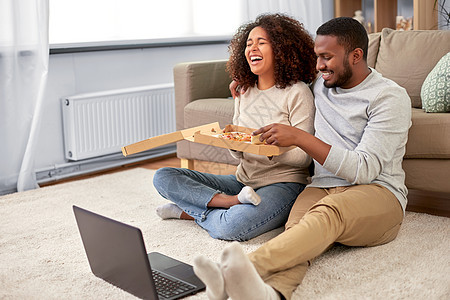 休闲,人食物的快乐的非裔美国人夫妇带着笔记本电脑家吃外卖比萨饼快乐的非裔美国人夫妇家吃披萨图片