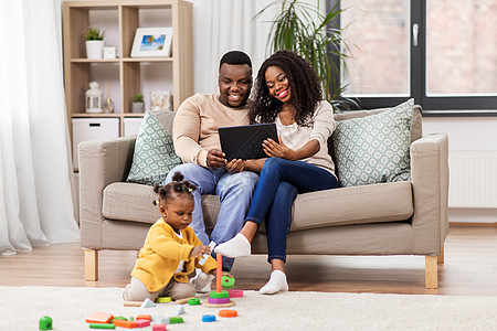 童年人的小非洲裔美国女婴玩玩具块父母用平板电脑电脑家家里有平板电脑玩具块图片