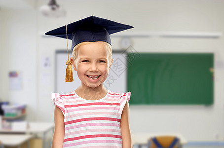 学校,教育学快乐的小女孩学士帽或黑板上的课堂背景戴着学士帽或灰泥板的快乐女孩图片