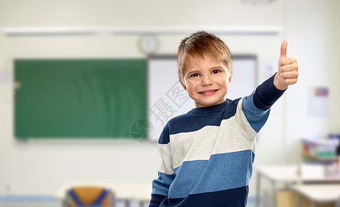 学校,教育手势微笑的小男孩穿着条纹套头衫,教室背景上竖起大拇指小男孩学校竖起大拇指图片