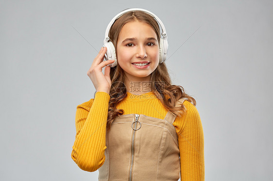 音频设备技术人员的微笑的少女耳机听音乐灰色背景戴耳机听音乐的十几岁女孩图片
