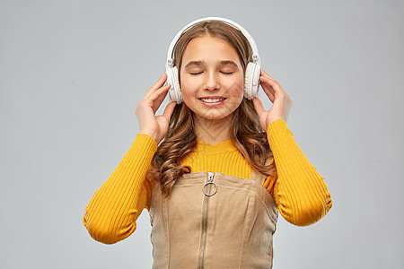 音频设备技术人员的微笑的少女耳机听音乐灰色背景戴耳机听音乐的十几岁女孩图片
