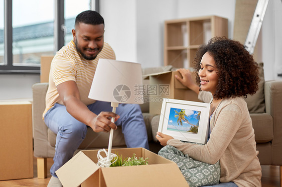 移动,人,维修房地产的快乐的非裔美国人夫妇包装材料家里的纸板箱幸福的夫妇包装盒搬到新家图片