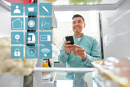 健康的饮食,技术饮食快乐的中年男子与智能手机列出必要的食物冰箱厨房蓝色白色智能家居应用图标有智能手机的男人冰图片