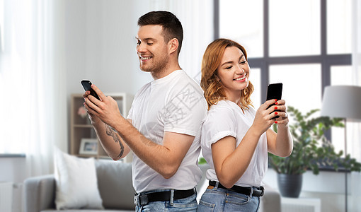 技术人的幸福的夫妇穿着白色T恤与智能手机家庭背景穿着白色T恤智能手机的幸福夫妇图片