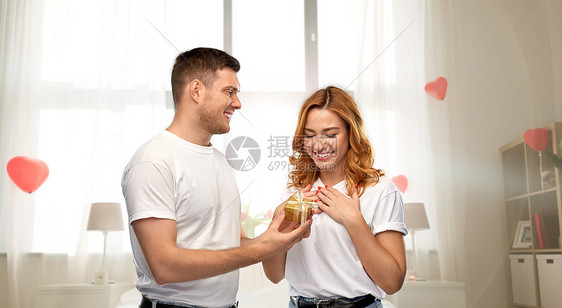 关系,假期情人节的幸福的夫妇穿着白色t恤,卧室装饰心形气球背景上有礼物幸福的夫妇情人节家里带礼物图片