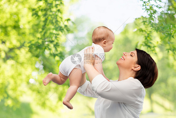 家庭,孩子父母的快乐的微笑中年母亲抱着小宝贝女儿绿色的自然背景快乐的中年母亲小女儿图片