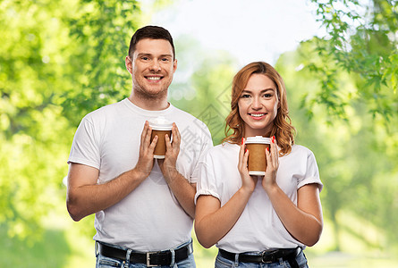 人际关系人的幸福夫妇的肖像白色T恤与外卖咖啡杯绿色的自然背景带外卖咖啡杯的幸福夫妇的肖像图片