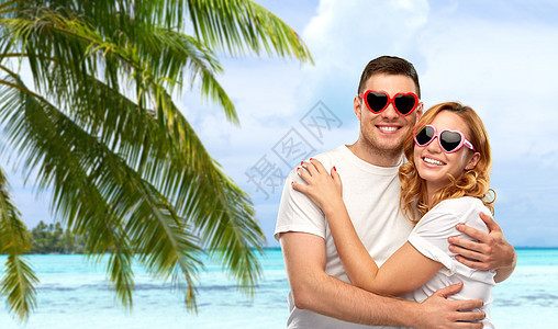 夏季配饰,情人节爱情幸福夫妇的肖像白色T恤心形太阳镜热带海滩背景法属波利尼西亚穿着白色T恤太阳镜的幸福夫妇图片