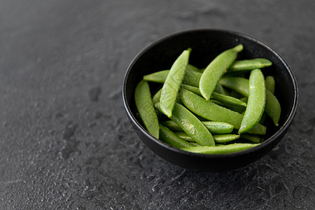 蔬菜,食物烹饪碗中的豌豆潮湿的石板石背景碗里的豌豆潮湿的石板石背景上图片