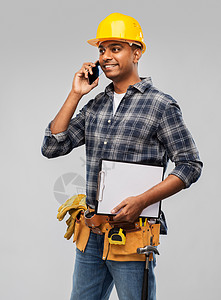 职业,建筑建筑快乐的微笑印度工人或建筑工人头盔呼叫智能手机灰色背景印度建筑工人头盔调用智能手机图片