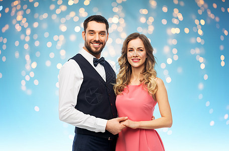 人们的幸福的夫妇穿着派服装,蓝色背景的假日灯上穿着派衣服的幸福夫妇图片